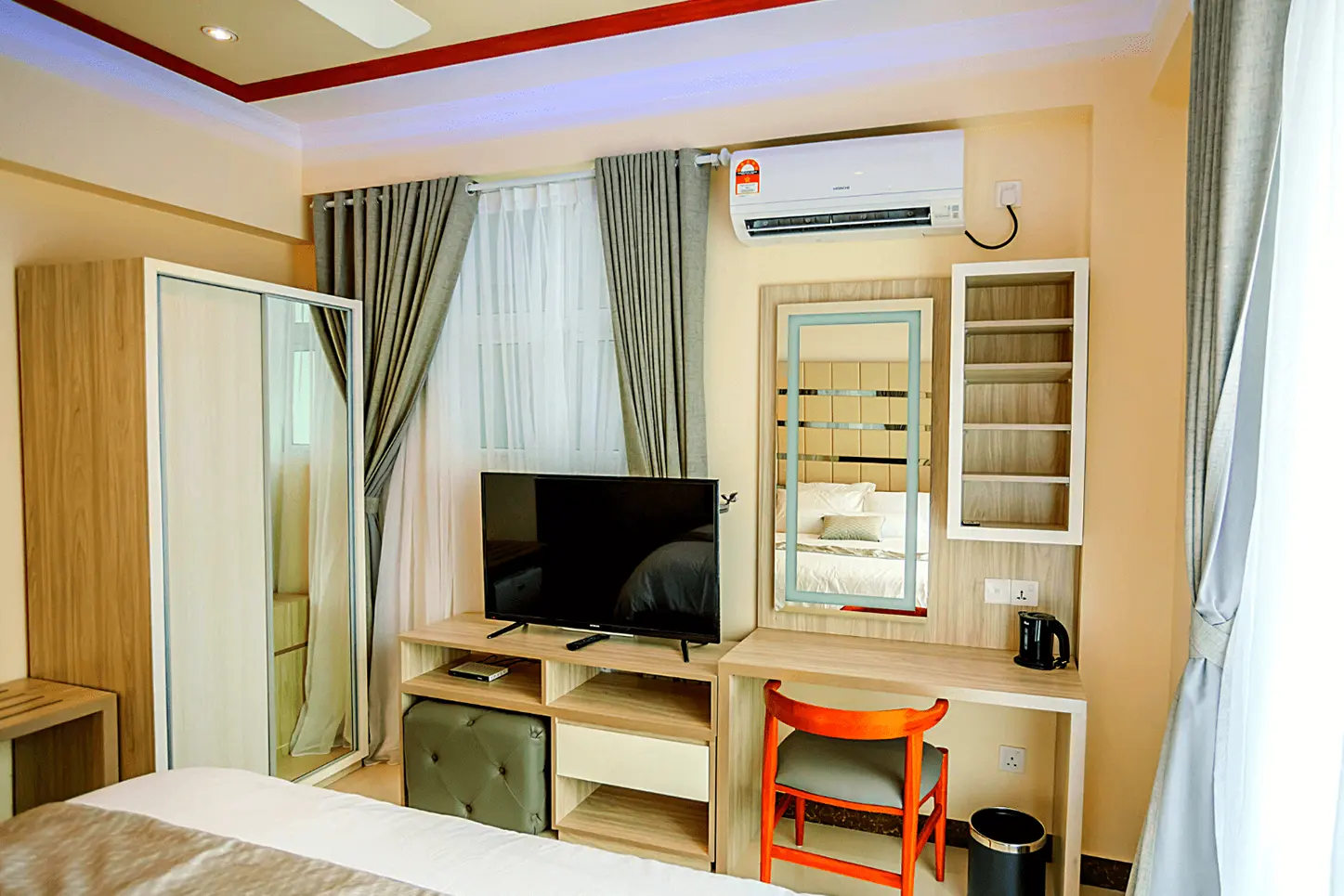 Relax in our neutral-toned bedroom with vanity, storage, and modern amenities for a serene hotel stay.