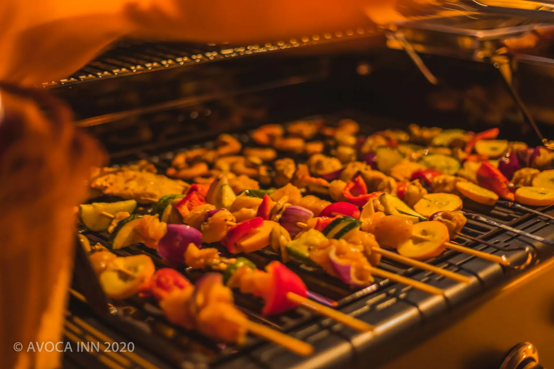 Colorful meat and vegetable skewers sizzle on the grill at Avoca Inn, promising a delicious meal.