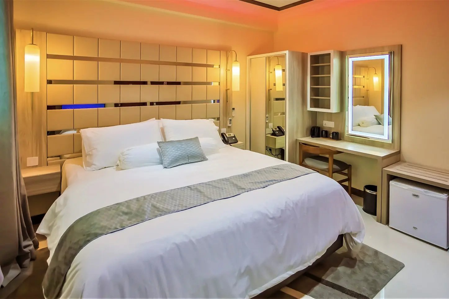 A luxurious hotel room with a comfortable bed, modern vanity, and soothing neutral decor provides a relaxing stay.