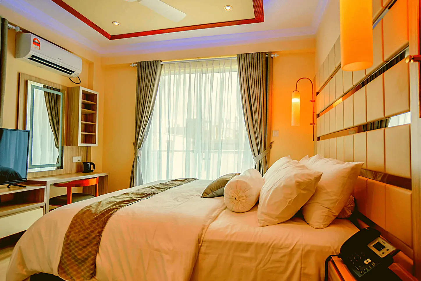Bright and inviting hotel room featuring a comfortable bed, vanity, and air conditioning.