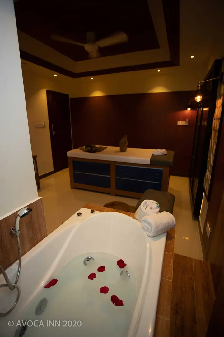 A luxury spa bathroom features a rose petal-filled tub and massage table for ultimate relaxation.